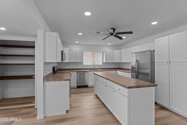 kitchen with white cabinetry, a center island, ceiling fan, backsplash, and appliances with stainless steel finishes