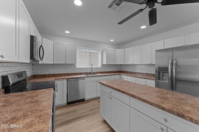 kitchen with decorative backsplash, ceiling fan, white cabinets, and stainless steel appliances