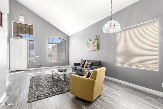 living area featuring high vaulted ceiling, a chandelier, baseboards, and wood finished floors