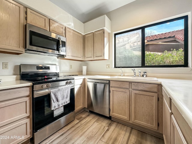 kitchen with light brown cabinets, light wood-type flooring, stainless steel appliances, and sink