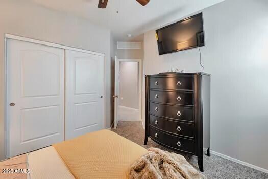 bedroom featuring light colored carpet, a closet, and ceiling fan