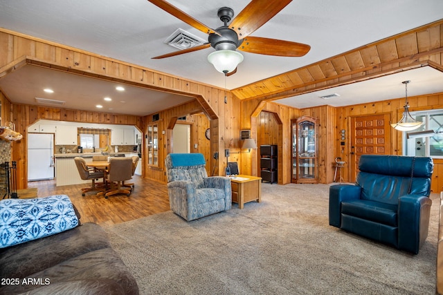 3384 Turkey Run, Overgaard, AZ 85933 - living room featuring wood walls, a ceiling fan, arched walkways, light carpet, and beamed ceiling