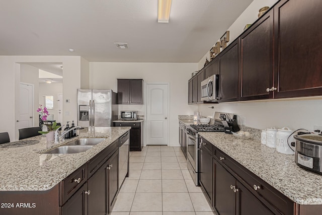 kitchen with sink, appliances with stainless steel finishes, dark brown cabinetry, and light tile patterned floors