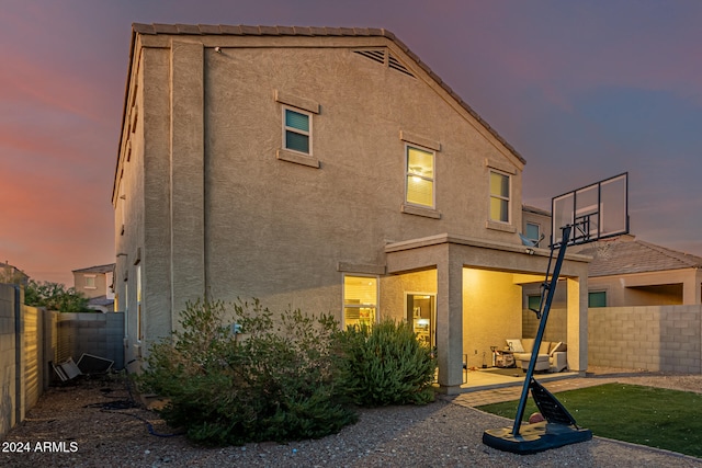 back house at dusk with a patio area