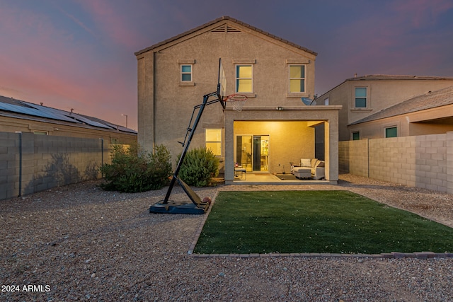 back house at dusk featuring a patio and a yard