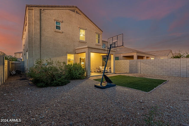 back house at dusk with a patio area