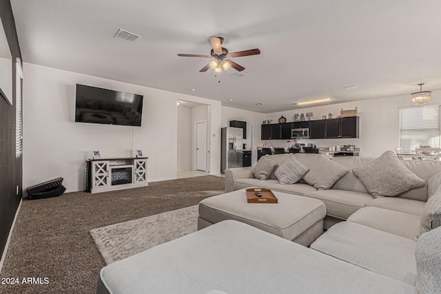 living room with ceiling fan with notable chandelier and carpet