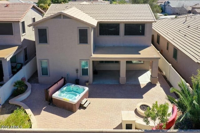 back of property featuring a patio and an outdoor hot tub