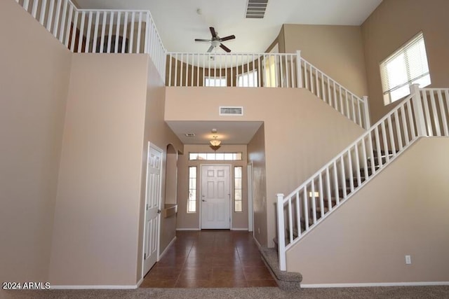 carpeted foyer featuring a high ceiling and ceiling fan