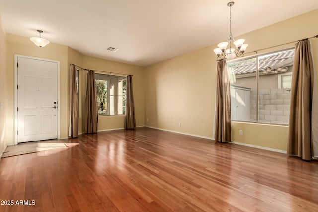 spare room featuring an inviting chandelier and hardwood / wood-style flooring