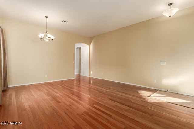 unfurnished room with hardwood / wood-style floors and an inviting chandelier