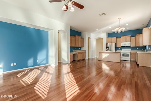 kitchen featuring white appliances, dark wood-type flooring, a kitchen island, pendant lighting, and ceiling fan with notable chandelier