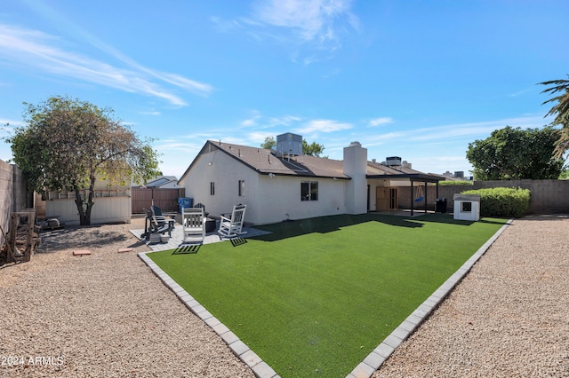 rear view of house featuring an outdoor fire pit, a patio area, a fenced backyard, and a lawn