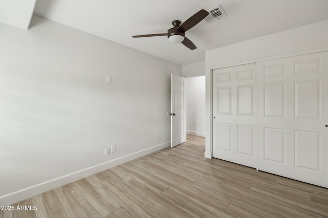 unfurnished bedroom featuring a closet, visible vents, light wood-style floors, ceiling fan, and baseboards