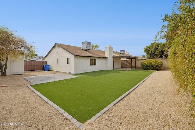 rear view of property featuring central AC unit, a fenced backyard, a lawn, stucco siding, and a patio area