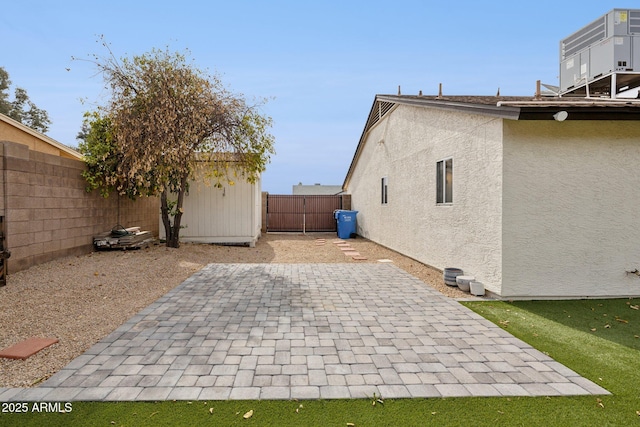 exterior space with a fenced backyard, an outdoor structure, stucco siding, a storage unit, and a patio area