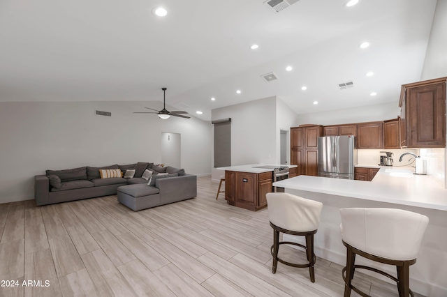 kitchen featuring kitchen peninsula, a kitchen breakfast bar, lofted ceiling, stainless steel refrigerator, and light hardwood / wood-style flooring