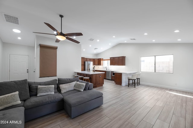 living room featuring lofted ceiling, light wood-style flooring, visible vents, and recessed lighting