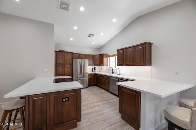 kitchen with visible vents, a breakfast bar area, a peninsula, stainless steel appliances, and light countertops