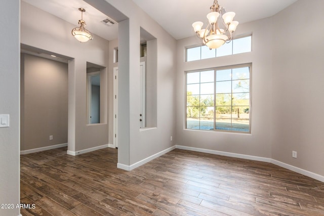 unfurnished room featuring dark wood-type flooring and a notable chandelier