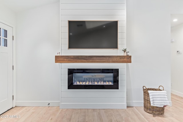 room details featuring a large fireplace, wood finished floors, and baseboards