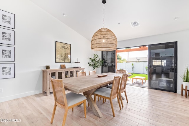 dining area with light wood-style floors, lofted ceiling, visible vents, and baseboards