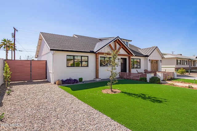 modern farmhouse featuring a front yard, fence, board and batten siding, and roof with shingles