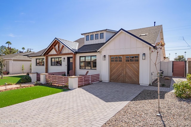 view of front of home featuring decorative driveway, a shingled roof, an attached garage, board and batten siding, and fence