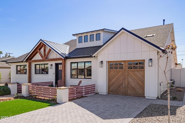 modern inspired farmhouse with decorative driveway, a shingled roof, an attached garage, board and batten siding, and a standing seam roof