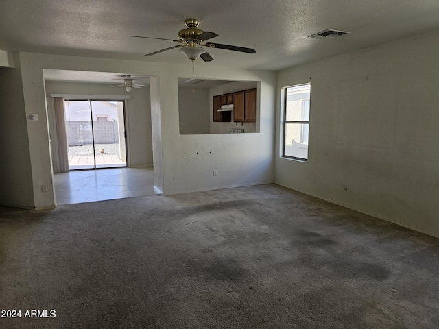 unfurnished room featuring a textured ceiling, carpet floors, and ceiling fan