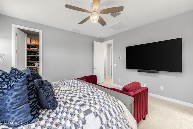 bedroom with a walk in closet, light colored carpet, a closet, and ceiling fan