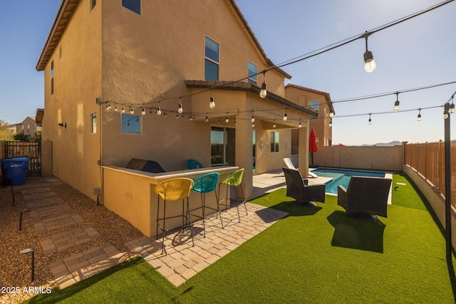 back of property featuring a fenced in pool, a patio area, and exterior bar