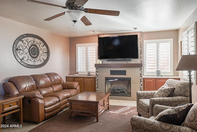 living room with ceiling fan, carpet floors, a textured ceiling, and a fireplace