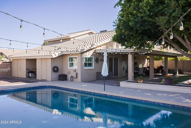 rear view of property featuring a fenced in pool, a pergola, and a patio