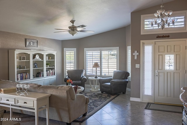 living room with vaulted ceiling, ceiling fan with notable chandelier, tile patterned floors, and a textured ceiling