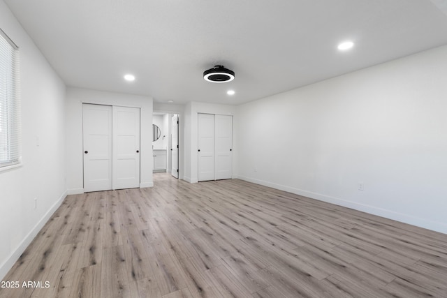 unfurnished bedroom with multiple closets and light hardwood / wood-style floors