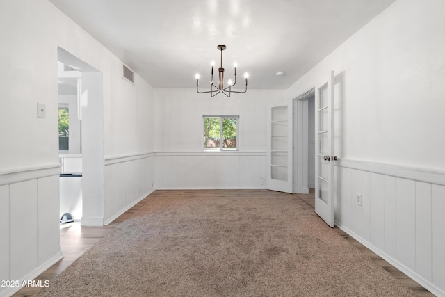 empty room with carpet flooring and an inviting chandelier