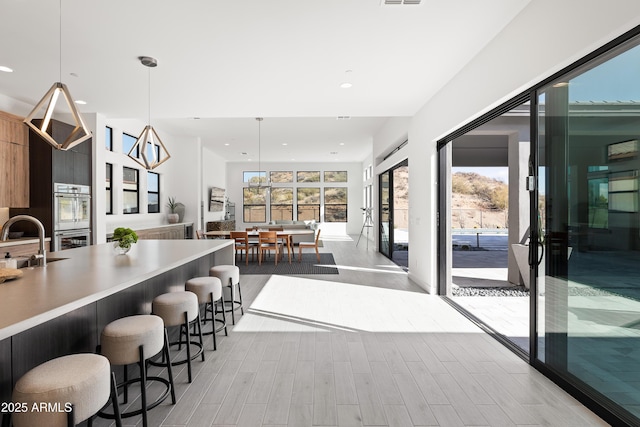 kitchen with pendant lighting, double oven, a wealth of natural light, and a breakfast bar area