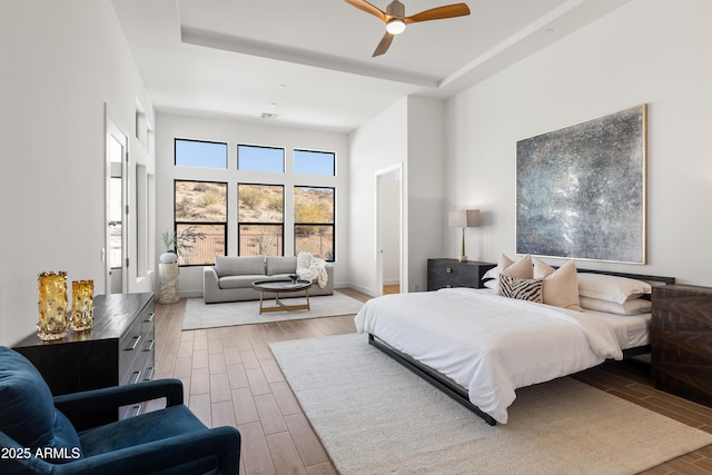 bedroom featuring ceiling fan, a towering ceiling, and a raised ceiling