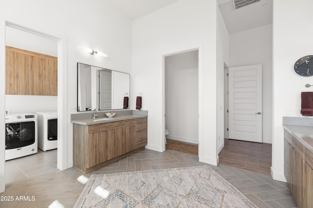 bathroom with vanity, parquet flooring, washing machine and dryer, and toilet