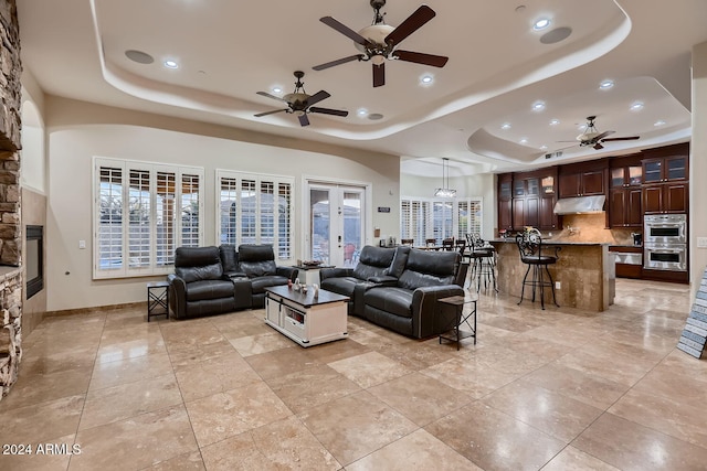 living room featuring french doors, a raised ceiling, and ceiling fan