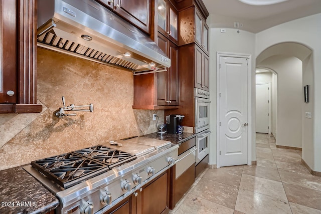 kitchen featuring appliances with stainless steel finishes, tasteful backsplash, and dark stone countertops