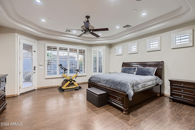 bedroom featuring a raised ceiling, ceiling fan, dark hardwood / wood-style floors, and access to exterior