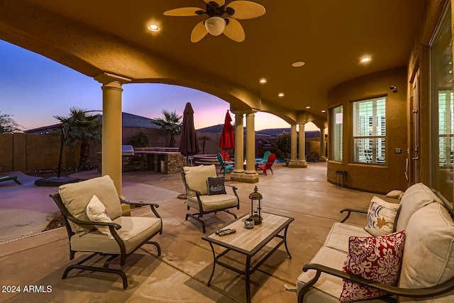 patio terrace at dusk with ceiling fan and an outdoor living space