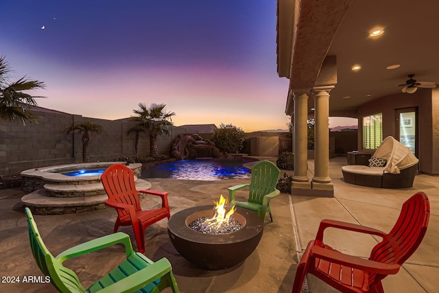 patio terrace at dusk with a fire pit, ceiling fan, a swimming pool with hot tub, and pool water feature