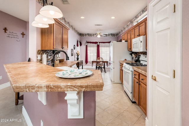 kitchen with tasteful backsplash, ceiling fan, white appliances, hanging light fixtures, and light tile flooring