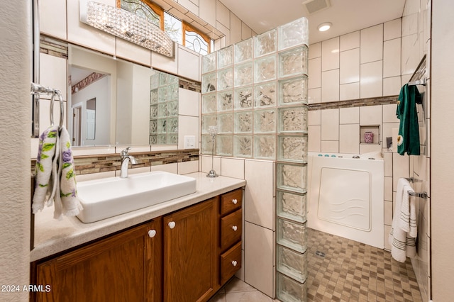 bathroom featuring tile walls, tasteful backsplash, tile flooring, washer / clothes dryer, and vanity