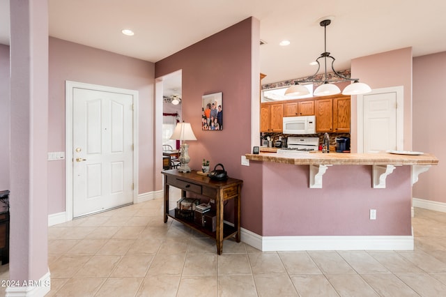 kitchen with light tile flooring, hanging light fixtures, tasteful backsplash, a breakfast bar, and white appliances