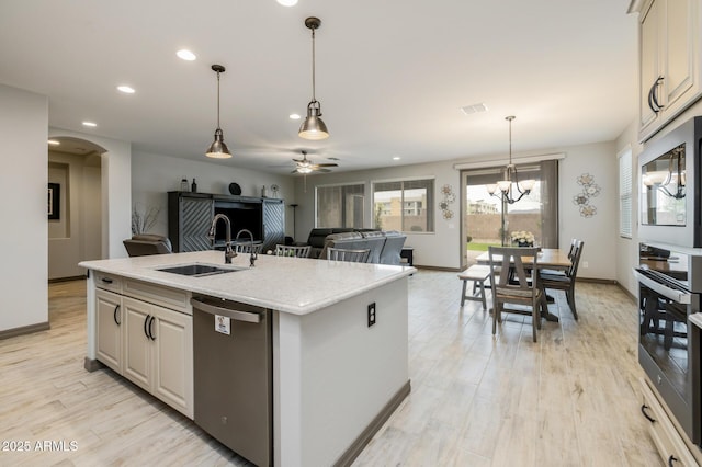 kitchen with visible vents, light wood-style floors, arched walkways, stainless steel appliances, and a sink