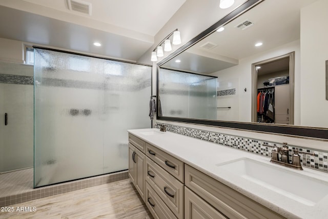 bathroom with a sink, visible vents, and a shower stall